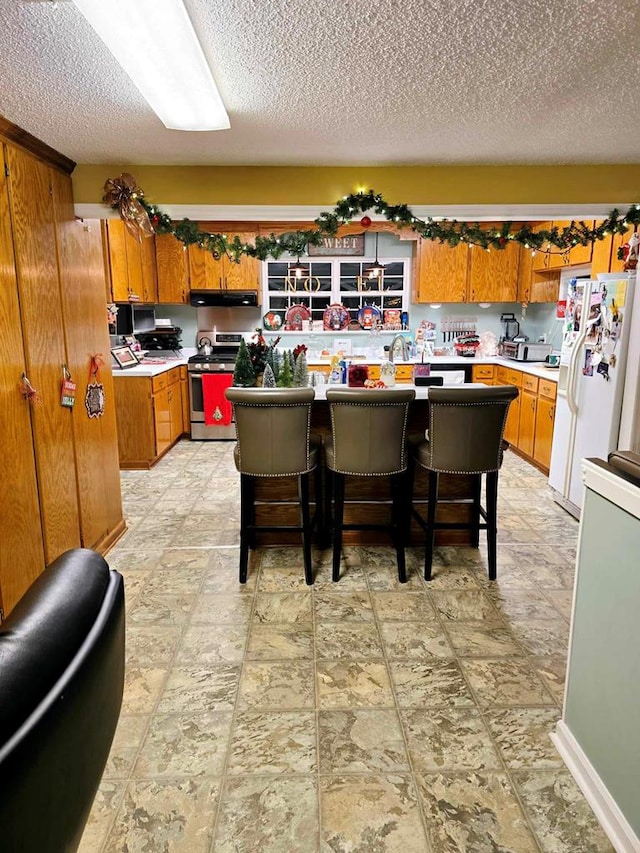 kitchen with white fridge with ice dispenser, a center island, a kitchen breakfast bar, a textured ceiling, and stainless steel electric stove