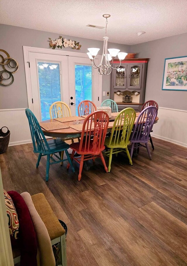 dining room featuring dark hardwood / wood-style flooring, french doors, a textured ceiling, and a chandelier