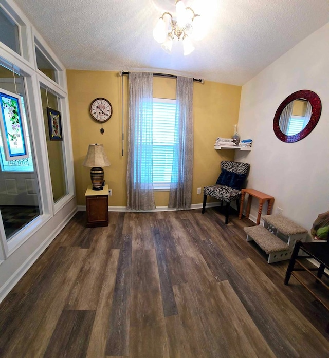 unfurnished room featuring dark wood-type flooring, a textured ceiling, and an inviting chandelier