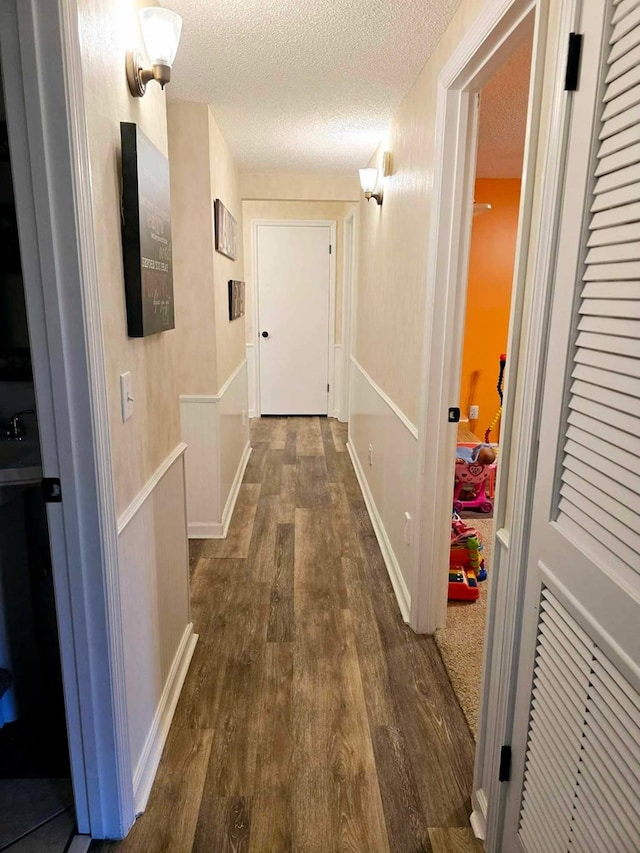 hall with a textured ceiling and dark wood-type flooring