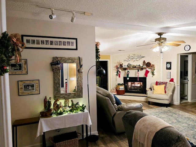 living room featuring a multi sided fireplace, track lighting, wood-type flooring, and a textured ceiling