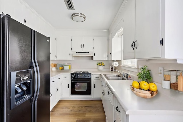 kitchen with under cabinet range hood, light countertops, crown molding, black appliances, and a sink