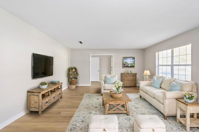 living area featuring light wood-style floors, visible vents, and baseboards