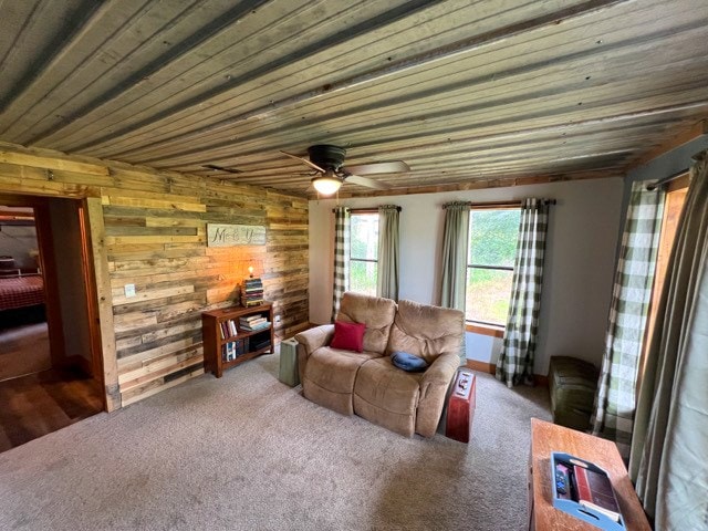 living room with ceiling fan, dark carpet, and wooden walls