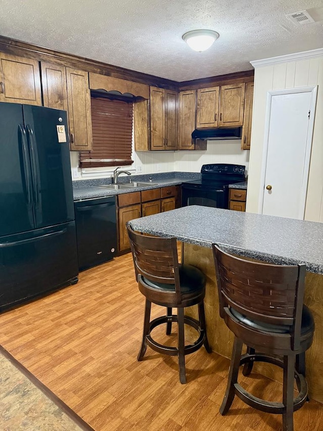 171 Merrydell Dr, Ozark, AL 36360 - kitchen featuring black appliances, under cabinet range hood, a textured ceiling, light wood-style floors, and dark countertops