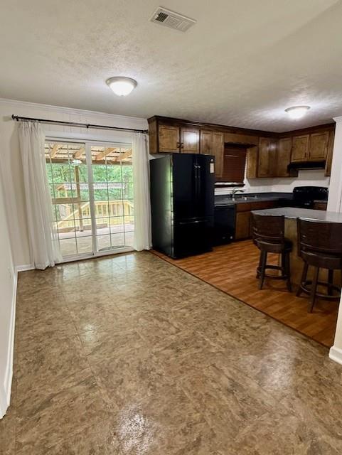 171 Merrydell Dr, Ozark, AL 36360 - kitchen with black appliances, dark countertops, crown molding, under cabinet range hood, and a kitchen breakfast bar