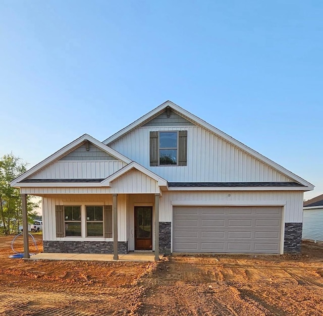 view of front of house with a porch, stone siding, and dirt driveway