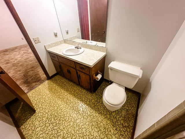 bathroom featuring baseboards, vanity, and toilet