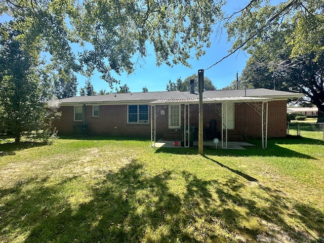 rear view of house featuring brick siding, a patio area, fence, and a yard