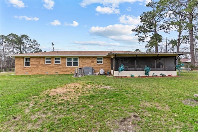 back of house featuring a sunroom, crawl space, brick siding, and a yard