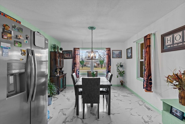 dining space featuring marble finish floor, baseboards, a textured ceiling, and an inviting chandelier