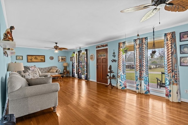 living area with crown molding, baseboards, and wood finished floors