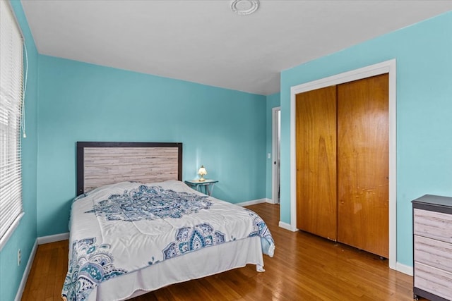 bedroom with a closet, baseboards, and wood finished floors