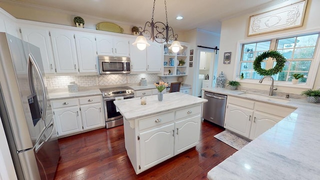 kitchen featuring dark wood-style flooring, a sink, ornamental molding, stainless steel appliances, and a barn door