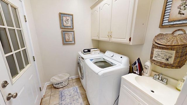 laundry room with baseboards, light tile patterned floors, washer and dryer, cabinet space, and a sink