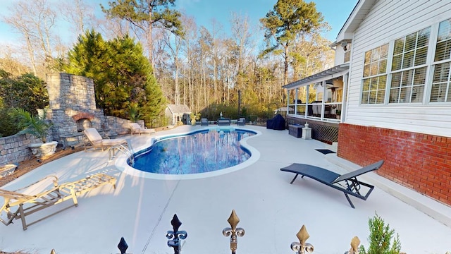 view of swimming pool with exterior fireplace, a fenced in pool, and a patio