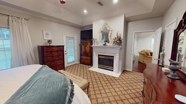 bedroom featuring visible vents, crown molding, a fireplace with flush hearth, recessed lighting, and a raised ceiling