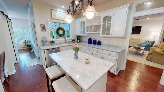 kitchen with a sink, stainless steel dishwasher, dark wood-style floors, a barn door, and glass insert cabinets