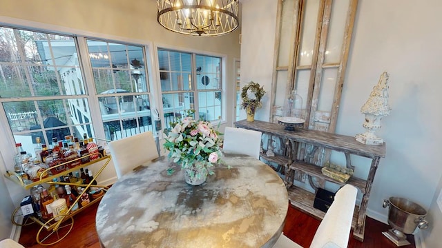 dining room with plenty of natural light, wood finished floors, baseboards, and a chandelier