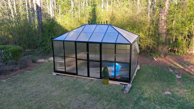 view of greenhouse with a yard and a wooded view