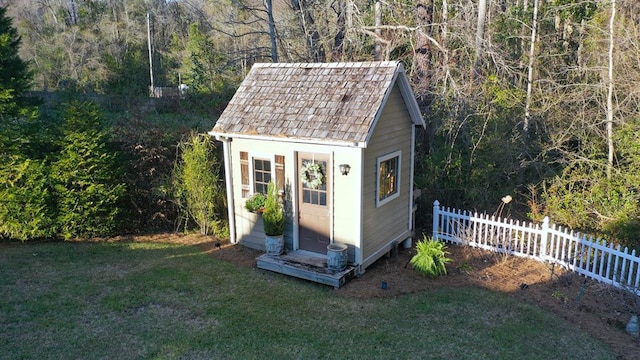 view of outbuilding with an outbuilding, a view of trees, and fence