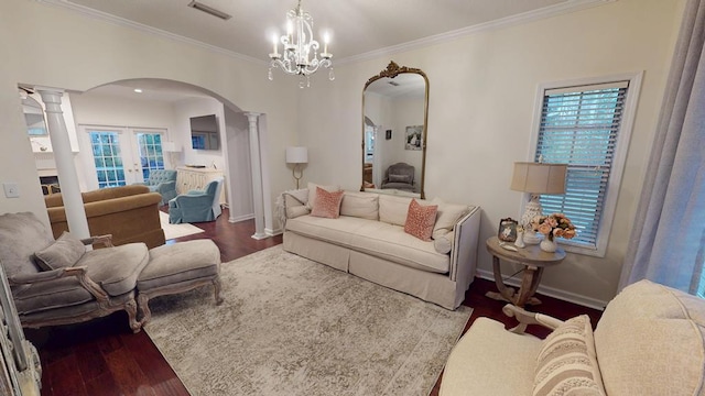 living area featuring wood finished floors, visible vents, decorative columns, arched walkways, and crown molding