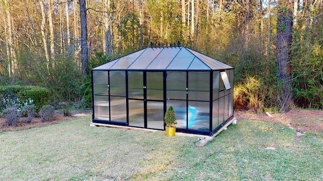 view of greenhouse with a forest view and a yard