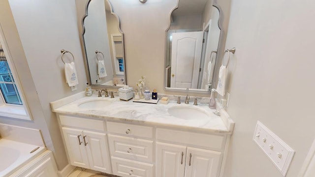 bathroom with double vanity, a bathtub, and a sink