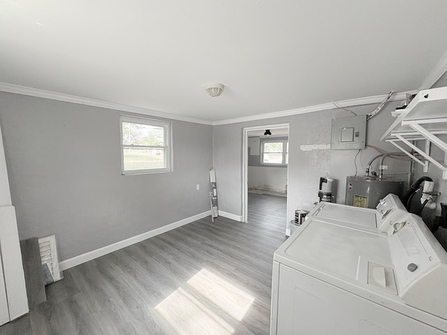 clothes washing area featuring washing machine and dryer, water heater, light hardwood / wood-style flooring, and ornamental molding