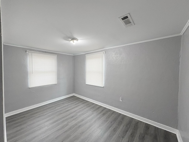 empty room featuring a healthy amount of sunlight, crown molding, and wood-type flooring