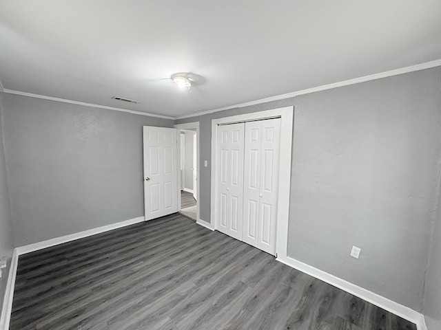 unfurnished bedroom with dark hardwood / wood-style floors, a closet, and ornamental molding