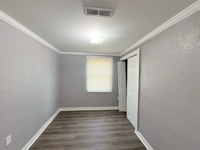 unfurnished bedroom featuring a closet, crown molding, and dark hardwood / wood-style flooring