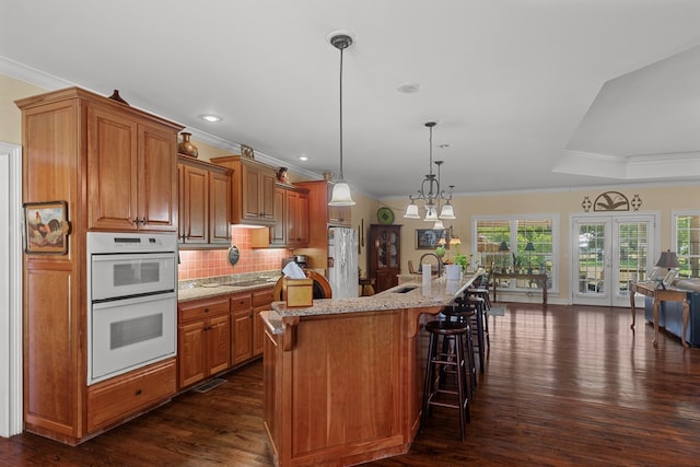 206 N Main St, Columbia, AL 36319 - kitchen featuring double oven, an island with sink, a kitchen breakfast bar, hanging light fixtures, and light stone countertops