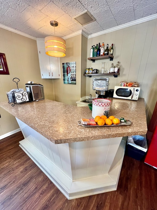 1503 Buena Vista Dr, Dothan, AL 36303 - kitchen with white microwave, wood finished floors, ornamental molding, a peninsula, and a breakfast bar area
