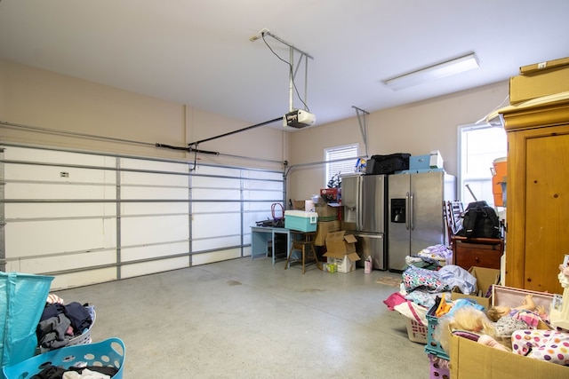 garage featuring stainless steel refrigerator with ice dispenser and a garage door opener