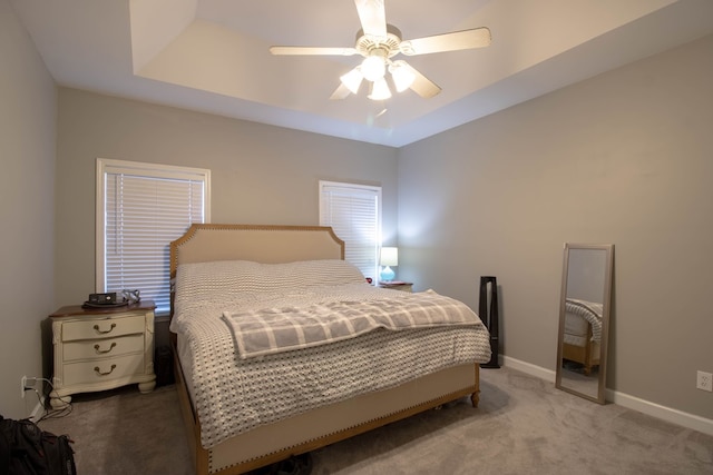 carpeted bedroom with a tray ceiling and ceiling fan