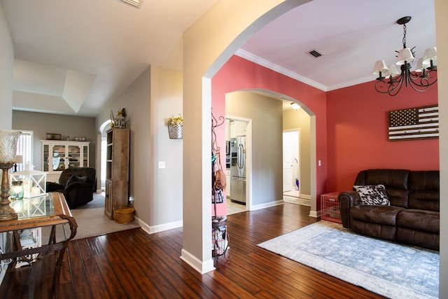 living room featuring ornamental molding, dark wood-type flooring, and a notable chandelier