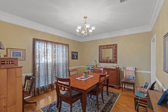 dining area featuring a notable chandelier, crown molding, and light hardwood / wood-style floors