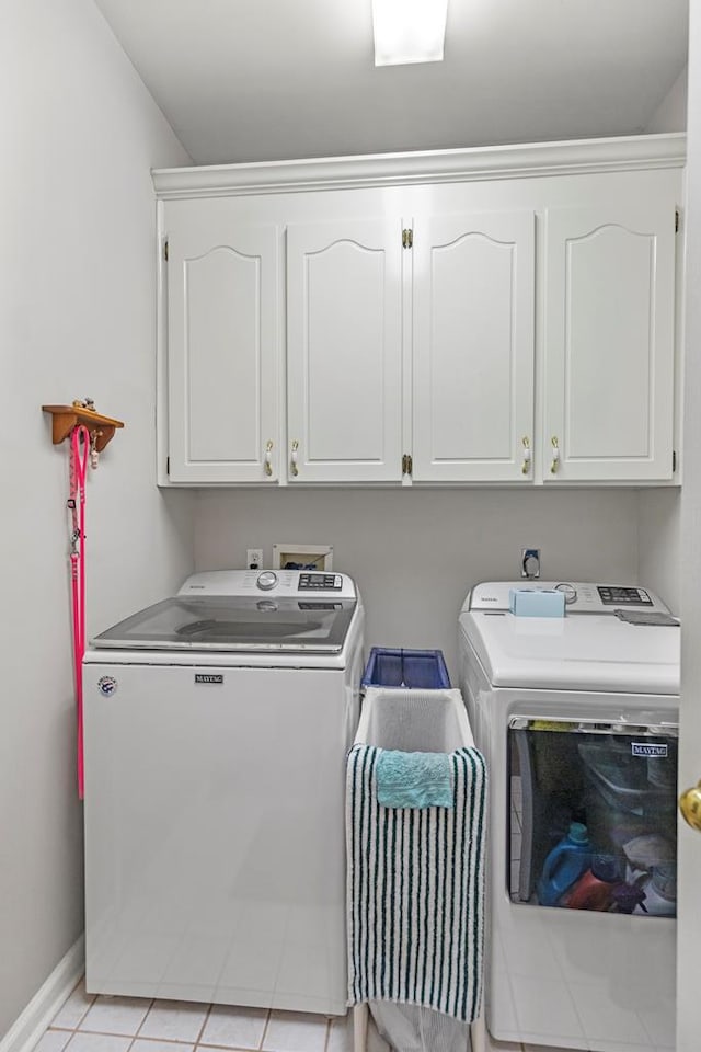 washroom with light tile patterned flooring, cabinets, and washer and clothes dryer