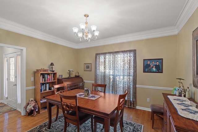 dining area with hardwood / wood-style floors, crown molding, and a notable chandelier