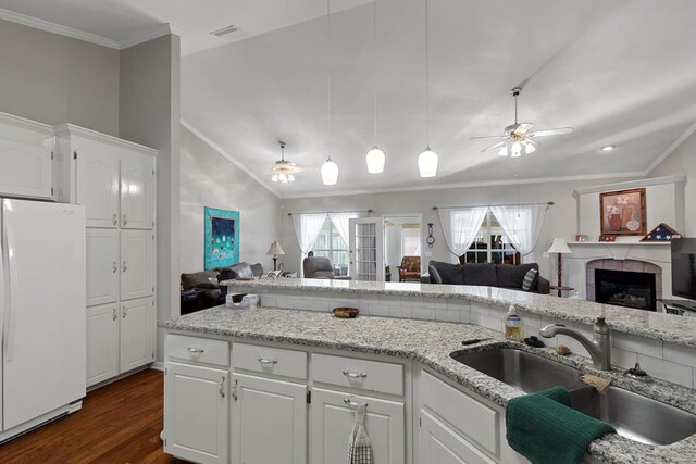 kitchen with sink, white cabinets, vaulted ceiling, and white fridge