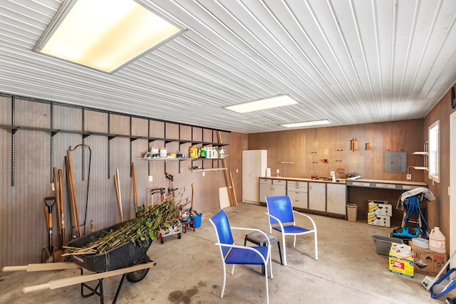 basement with wood walls, electric panel, and a workshop area