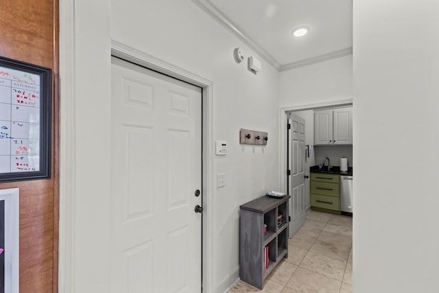 interior space with light tile patterned floors, crown molding, and sink