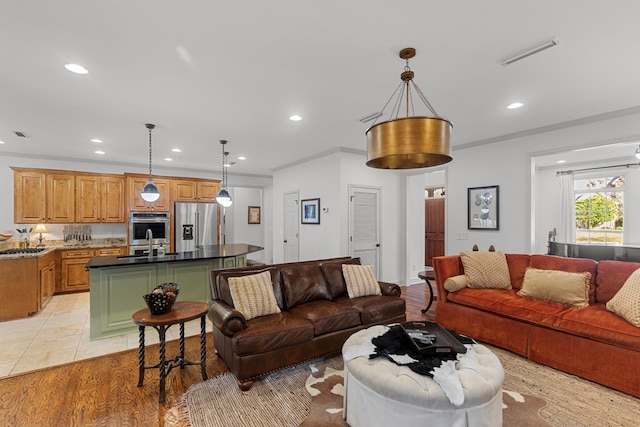 living room with light tile patterned floors, ornamental molding, and sink