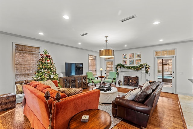 living room with crown molding, light hardwood / wood-style flooring, and a brick fireplace