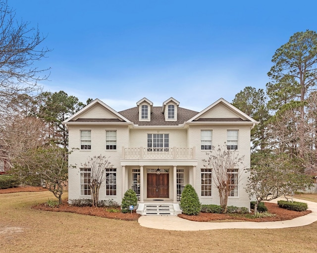 view of front of home with a balcony and a front yard