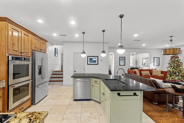 kitchen featuring sink, hanging light fixtures, a kitchen island with sink, appliances with stainless steel finishes, and green cabinetry