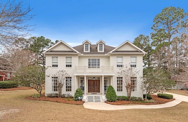 view of front of house featuring a balcony and a front lawn