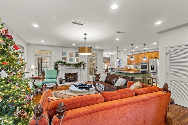 living room featuring hardwood / wood-style flooring, ornamental molding, and a brick fireplace