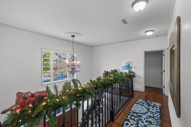 hallway with crown molding, dark wood-type flooring, and an inviting chandelier